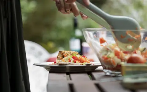 Un delizioso pasto all'aperto, perfetto per un weekend in fattoria. Un piatto con pannocchia grigliata e insalata fresca, servito da una ciotola trasparente.