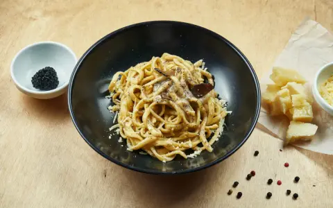 Un piatto di pasta al tartufo, un sapore autentico del cibo perugino, con scaglie di parmigiano e pepe nero.