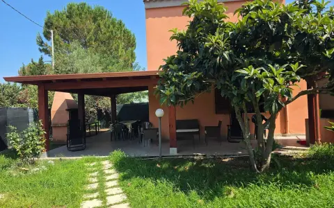 Veranda con tavolo e sedie, barbecue e alberi da frutto. Un angolo di pace tra i migliori agriturismi Sardegna sud.