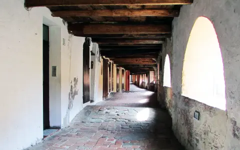 Portico con soffitto in legno e archi luminosi, pavimentazione in mattoni antichi. Un viaggio nella storia lungo la via degli asini a Brisighella.