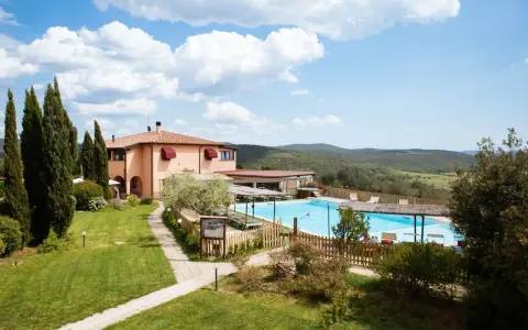 Un agriturismo in Toscana a Pasqua, con piscina azzurra e colline verdi sullo sfondo.