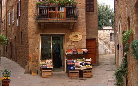Un piccolo negozio di frutta e verdura in un vicolo di **paesi toscani**. Frutta fresca in cassette di legno, un balcone fiorito e l'atmosfera autentica.