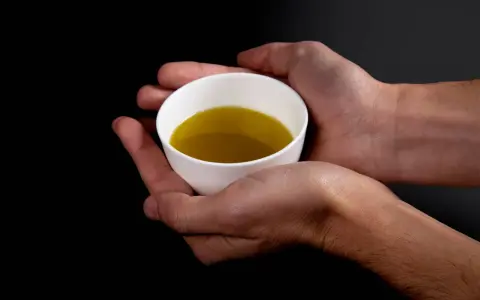 Mani che sorreggono una tazzina bianca con olio evo. Il suo significato è prezioso, un nettare dorato.