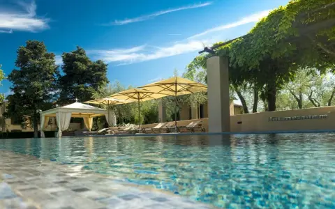 Piscina con lettini e ombrelloni in un agriturismo particolare nel Lazio, immerso nel verde.