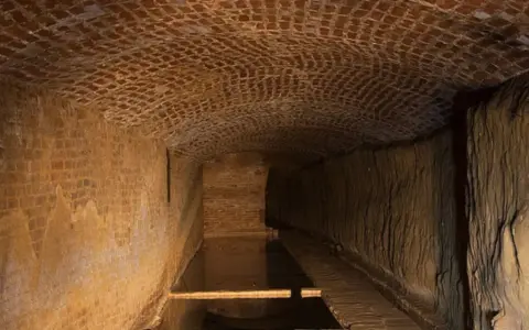 Antichi bottini di Siena, un labirinto sotterraneo di mattoni e terra, con un canale d'acqua.