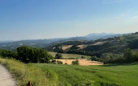Due persone in sella a cavalli godono di splendide passeggiate a cavallo in Umbria, tra colline verdi e campi dorati.