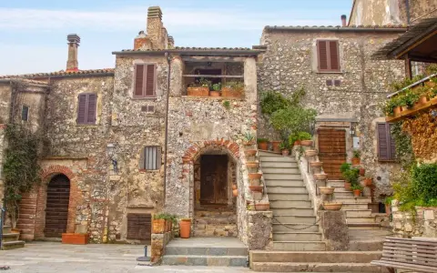 Un angolo di **Toscana, cosa vedere: borghi** antichi con case in pietra, scale fiorite e un'atmosfera senza tempo.