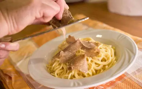 Un piatto di spaghetti conditi con tartufo fresco, un'esperienza culinaria tipica delle sagre tartufo toscana.