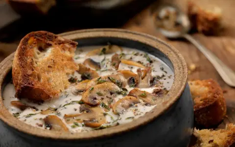 Una cremosa zuppa di funghi toscana, arricchita da erbe aromatiche e servita con crostini di pane abbrustolito.
