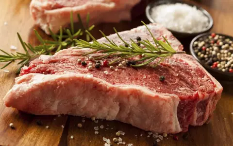 Bistecca alla fiorentina, un cibo succulento pronto per essere cucinato, con rosmarino, sale grosso e pepe.