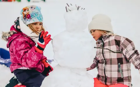 Bambini creano un pupazzo di neve in montagna, un vero natale in montagna con bambini che si divertono nella neve.