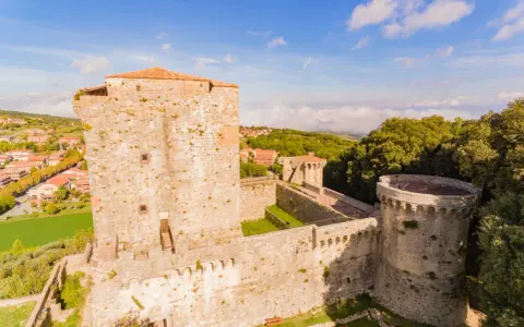 Il castello di Sarteano domina il borgo con le sue mura antiche e torri imponenti, circondato dal verde della campagna toscana.