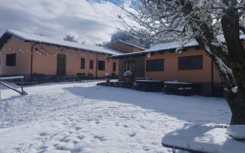 Agriturismo Acqua Bianca imbiancato dalla neve. Un paesaggio invernale incantevole con edifici color pesca e un cielo azzurro con nuvole bianche.