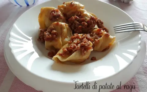 Tortelli di patate al ragù, un piatto gustoso e confortante, servito su un piatto bianco con una forchetta.