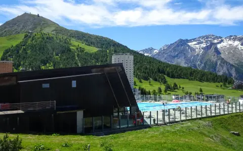 Una splendida piscina in montagna in Piemonte, con vista su verdi colline e cime innevate.