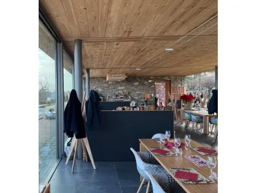 Interno di un agriturismo con tavoli apparecchiati, bancone in pietra e legno. L'agriturismo acqua terra sole offre un'atmosfera accogliente.