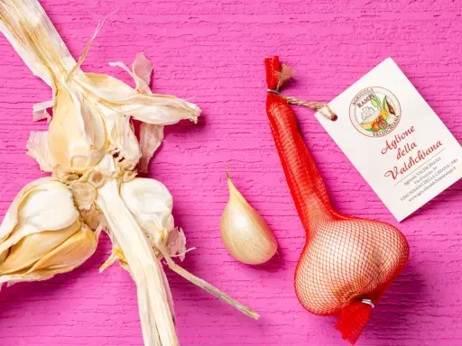 Aglione della Valdichiana, perfetto per le tue aglione ricette. Un bulbo intero e uno spicchio su sfondo rosa.