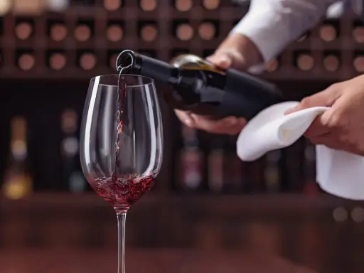 Un calice di vino rosso viene versato da una bottiglia, un momento perfetto per un tour enogastronomico Toscana.