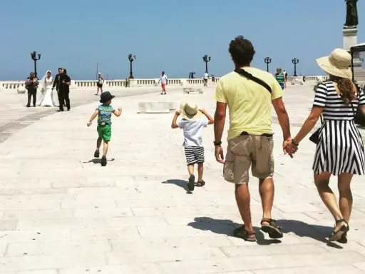 Famiglia in vacanza in Puglia con bambini, mentre passeggiano sul lungomare.