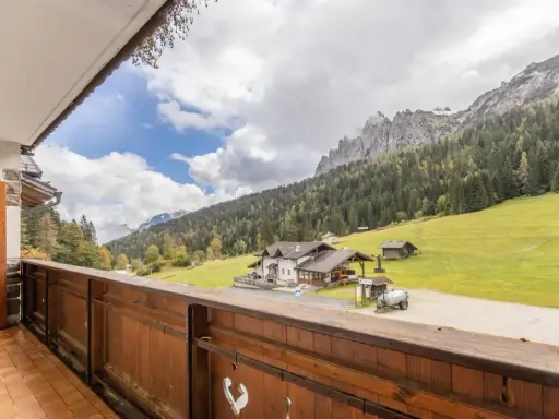Vista da un balcone su una casa di montagna con prati verdi e boschi. Perfetta per una vacanza in montagna estate.