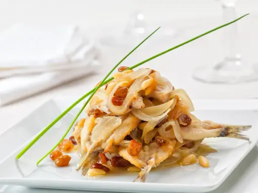 Sardine in saor, un classico dei piatti tipici veneti, con cipolle caramellate, uvetta e pinoli.