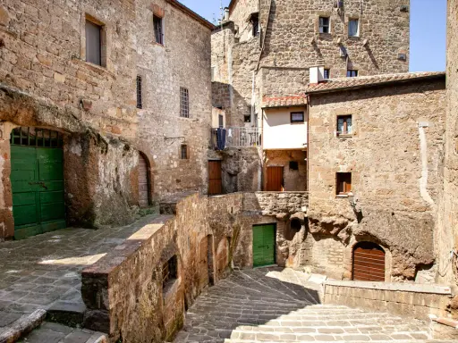 Un vicolo stretto con scale di pietra e case antiche in tufo, un'atmosfera da piccola Gerusalemme.