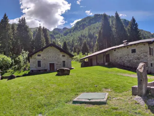 Agriturismi lombardia montagna: casette in pietra immerse nel verde, con boschi e montagne sullo sfondo.