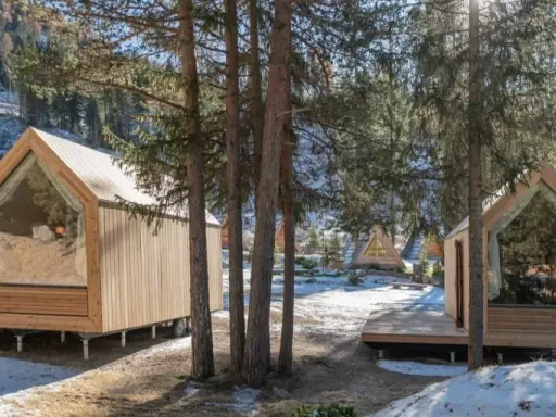 Accoglienti alloggi particolari nel Lazio, con cabine in legno e ampie vetrate immerse nel bosco innevato.