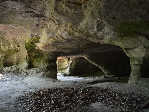 L'interno di una grotta scavata nella roccia, con nicchie e passaggi che ricordano Vitozza, la città perduta.