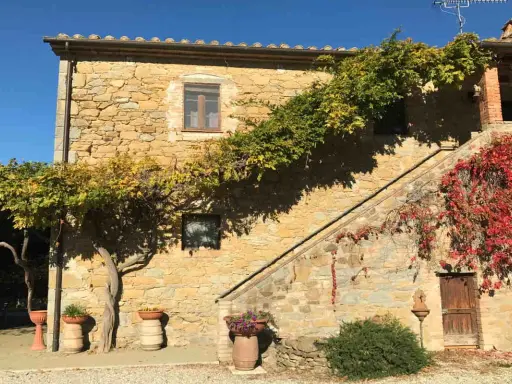 Agriturismi pet friendly in Umbria: casa in pietra con scala esterna e rampicanti colorati, ideale per vacanze con animali.