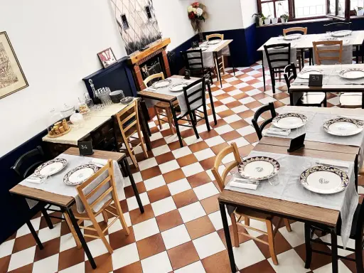 Tavoli apparecchiati in un ristorante, pronti per un'esperienza di **mangiare in Umbria**. Pavimento a scacchi, sedie in legno e dettagli eleganti.