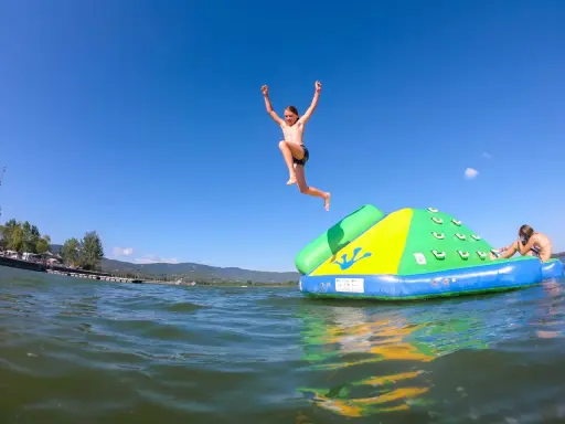 Bambini si divertono sul lago Trasimeno, uno salta da un gonfiabile mentre un altro si riposa.