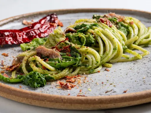 Spaghetti verdi con verdure, acciughe e peperoncino secco, un piatto tipico Basilicata che evoca sapori autentici.
