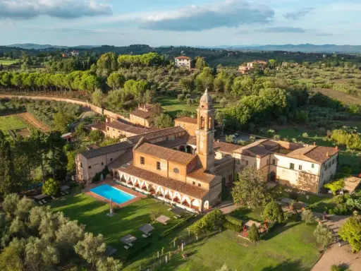 Un'antica dimora con campanile e una splendida piscina toscana, immersa nel verde delle colline.