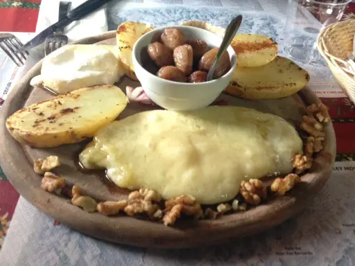 Piatto con formaggio fuso, patate arrosto, noci e cipolline. Un assaggio dei piatti tipici Valle d'Aosta.