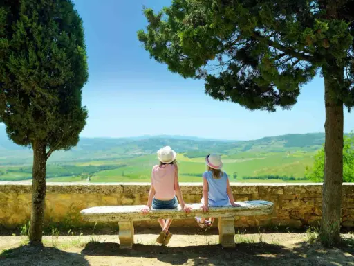 Due bambine con cappello ammirano il panorama collinare toscano, un perfetto weekend con bambini in Toscana.