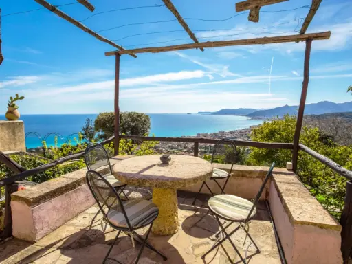 Terrazza con tavolo e sedie, vista mare e colline. Ideale per agriturismi entroterra ligure.