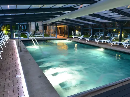 Piscina coperta con lettini e cascate d'acqua, un'oasi di relax tra le migliori spa in Umbria.
