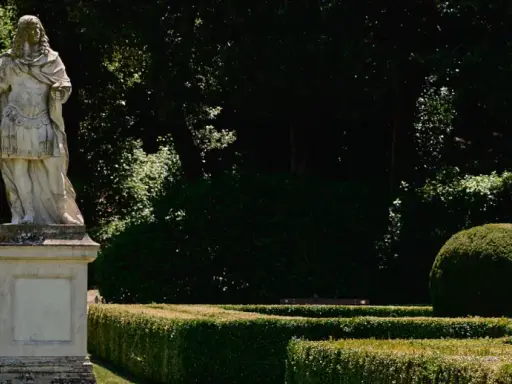 Statua romana domina la scalinata nei **Horti Leonini**. Giardini curati e alberi ombrosi creano un'atmosfera regale.