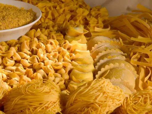 Varietà di pasta fresca, tra cui tortellini, ravioli e tagliatelle, che rappresentano i piatti tipici dell'Emilia Romagna.