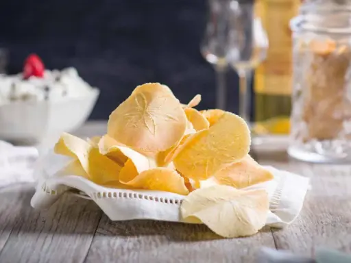 Delicati cialde, un dolce tipico toscano, su un tovagliolo ricamato. Sullo sfondo, una ciotola con crema e bicchieri.