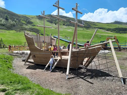 Un grande galeone di legno su un prato verde, perfetto per agriturismi per bambini in Piemonte. Bambini giocano a bordo.