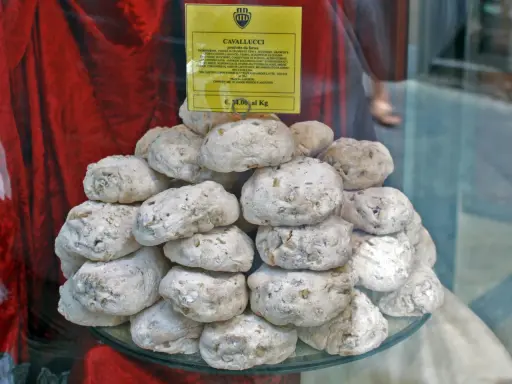 Dolce senese: cavallucci, biscotti rustici con noci e agrumi, impilati su un piatto di vetro.