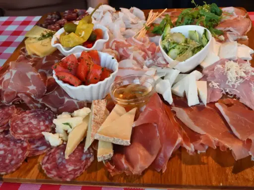 Tagliere ricco con salumi, formaggi, pomodori e sottaceti, un assaggio dei piatti tipici del Friuli Venezia Giulia.
