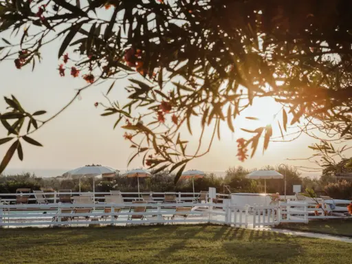 Tramonto dorato su una piscina con lettini e ombrelloni, un'oasi di pace tra i **posti romantici Toscana**.
