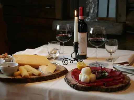 Tagliere con formaggi e bresaola, accompagnati da vino rosso e candela. Un assaggio dei piatti tipici Valtellina.