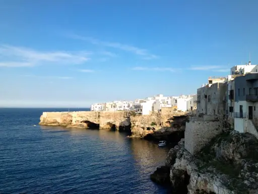 Scogliere bianche e case a picco sul mare blu, un'ottima idea per cosa visitare vicino Alberobello.