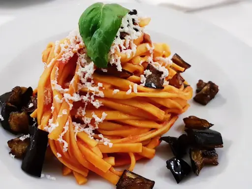 Pasta con melanzane fritte e ricotta salata, un classico su cosa mangiare in Sicilia. Un piatto gustoso e colorato.