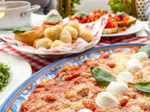 Un assaggio di cosa mangiare in Campania: gnocchi fritti, bruschette e un piatto di pasta al pomodoro e mozzarella.