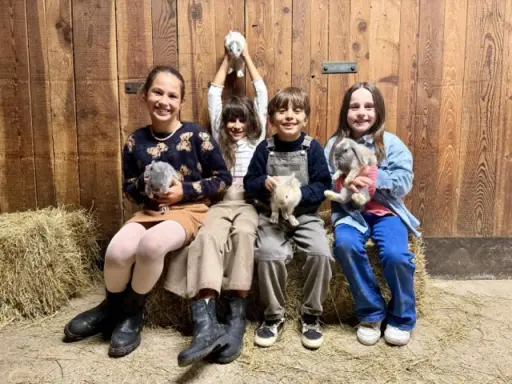 Bambini felici durante un'attività fattoria, tengono in braccio coniglietti soffici.